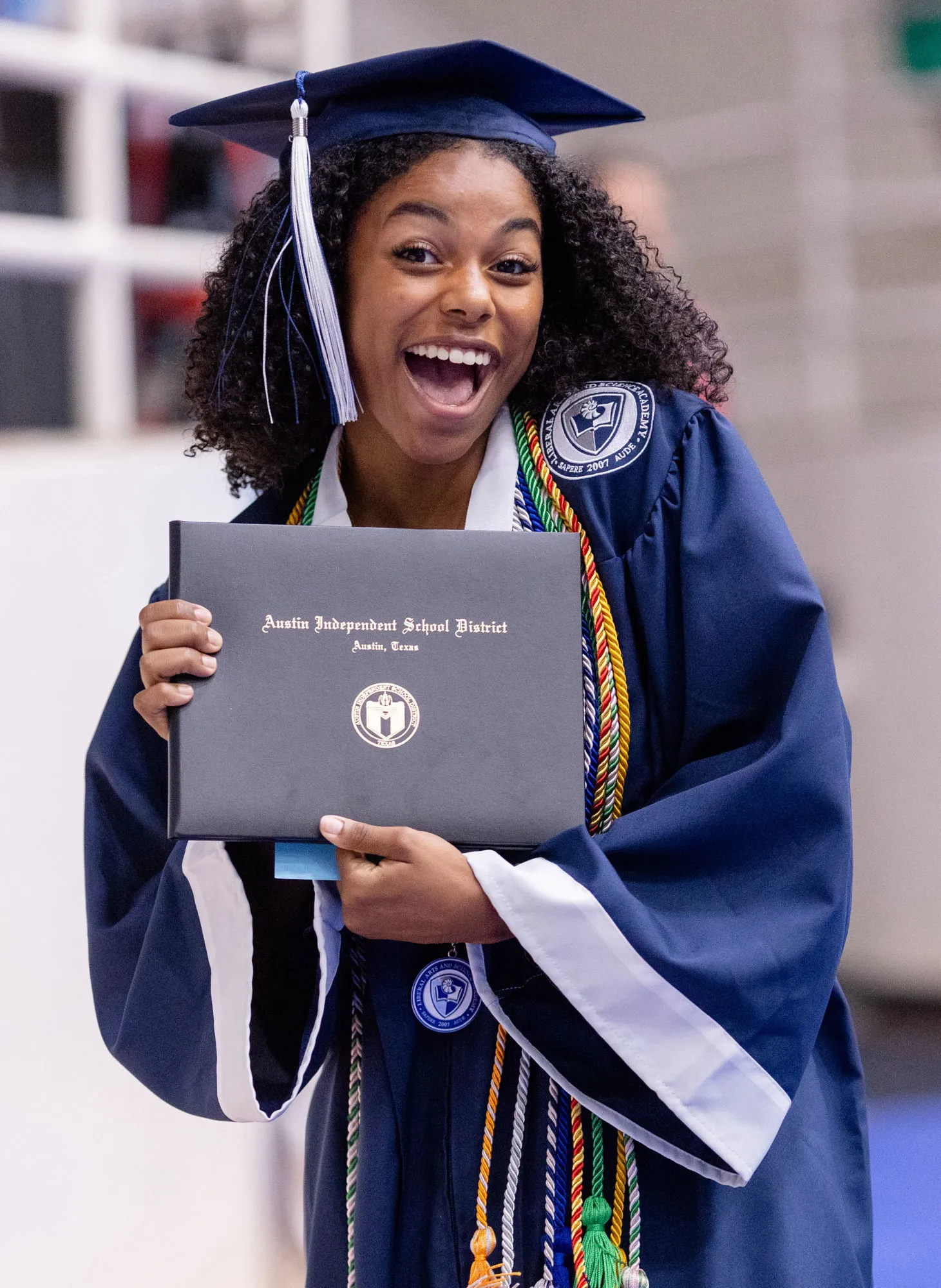 Joyful Austin ISD graduate holding her diploma at commencement